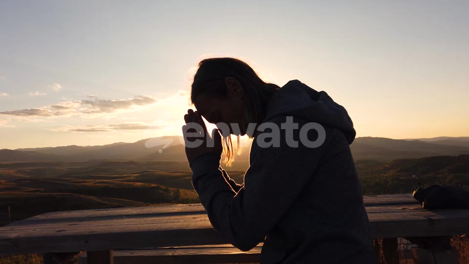 He bows his head, hands together, to the sky