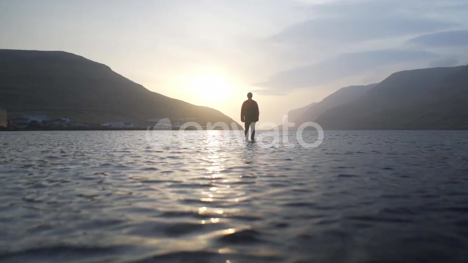 In the mountain lake at sunset, in silhouette, mountains on every side