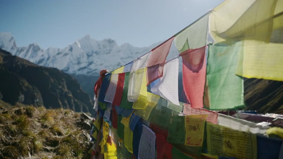 Prayer flags waving in the wind under the snow peaks, in slow motion
